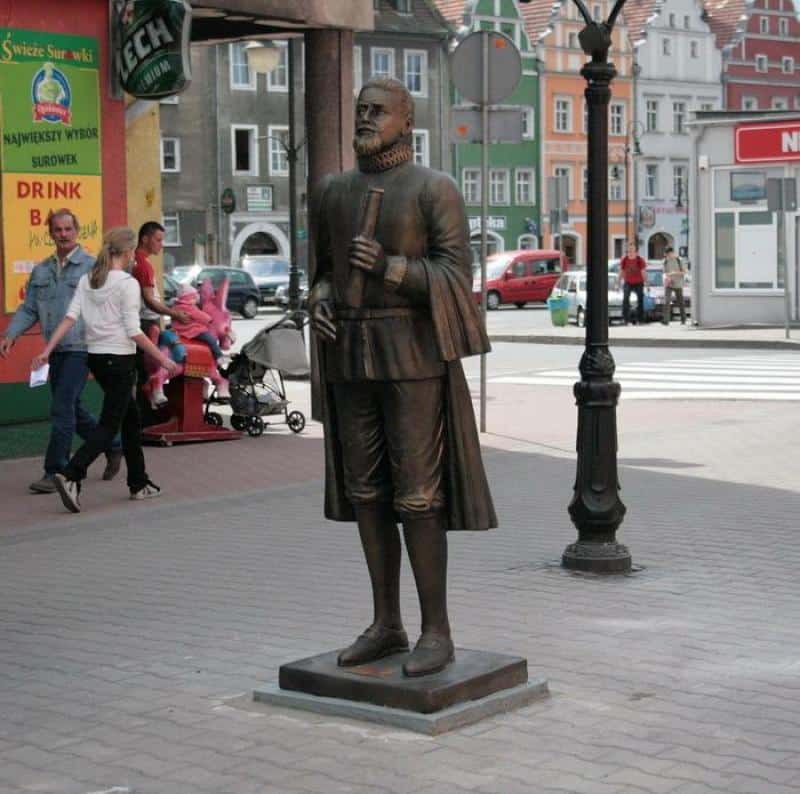 Pomnik - Kepler 1 Pomnik mężczyzny w historycznym stroju trzymającego zwój na ulicy w mieście.