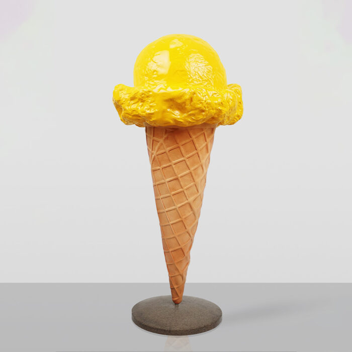 Rzeźba przedstawiająca lody o smaku cytrynowym na rożku waflowym, stojące na okrągłej podstawie, na jasnym tle.