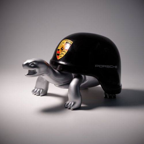 figura żółwia z czarną skorupą przypominającą hełm Porsche, wykonana z laminatu o srebrzystym, realistycznym wykończeniu