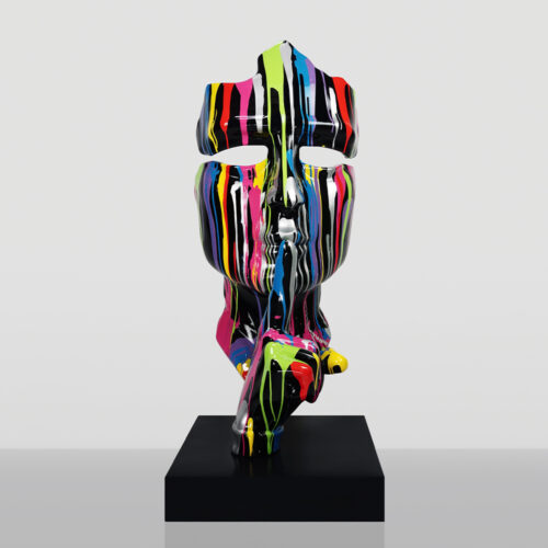 Nowoczesna rzeźba głowy z palcem na ustach w geście ciszy, pokryta kolorowymi, pionowymi smugami farby, stojąca na czarnym postumencie na szarym tle