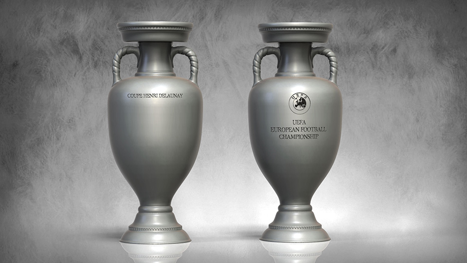 Symboliczne Trofea dla Euro 2024 4 Dwa srebrne puchary UEFA European Football Championship stojące obok siebie na jasnym tle, jeden z napisem COUPE HENRI DELAUNAY, drugi z logo UEFA i napisem UEFA EUROPEAN FOOTBALL CHAMPIONSHIP.