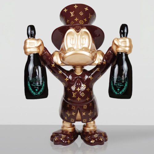 Figurka stylizowanego kaczora ubrana w ciemnoczerwony płaszcz i cylinder z wzorem Louis Vuitton, trzymająca w obu rękach dwie butelki szampana Dom Pérignon.