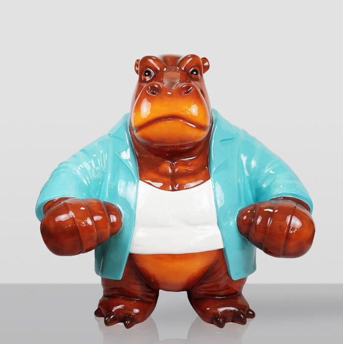 Błyszcząca ceramiczna figurka hipopotama stojącego na czterech łapach, ubranego w biały podkoszulek i jasnoniebieską marynarkę, na szarym tle